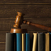 Mazo judicial golpeando su base, apoyada sobre unos libros en vertical